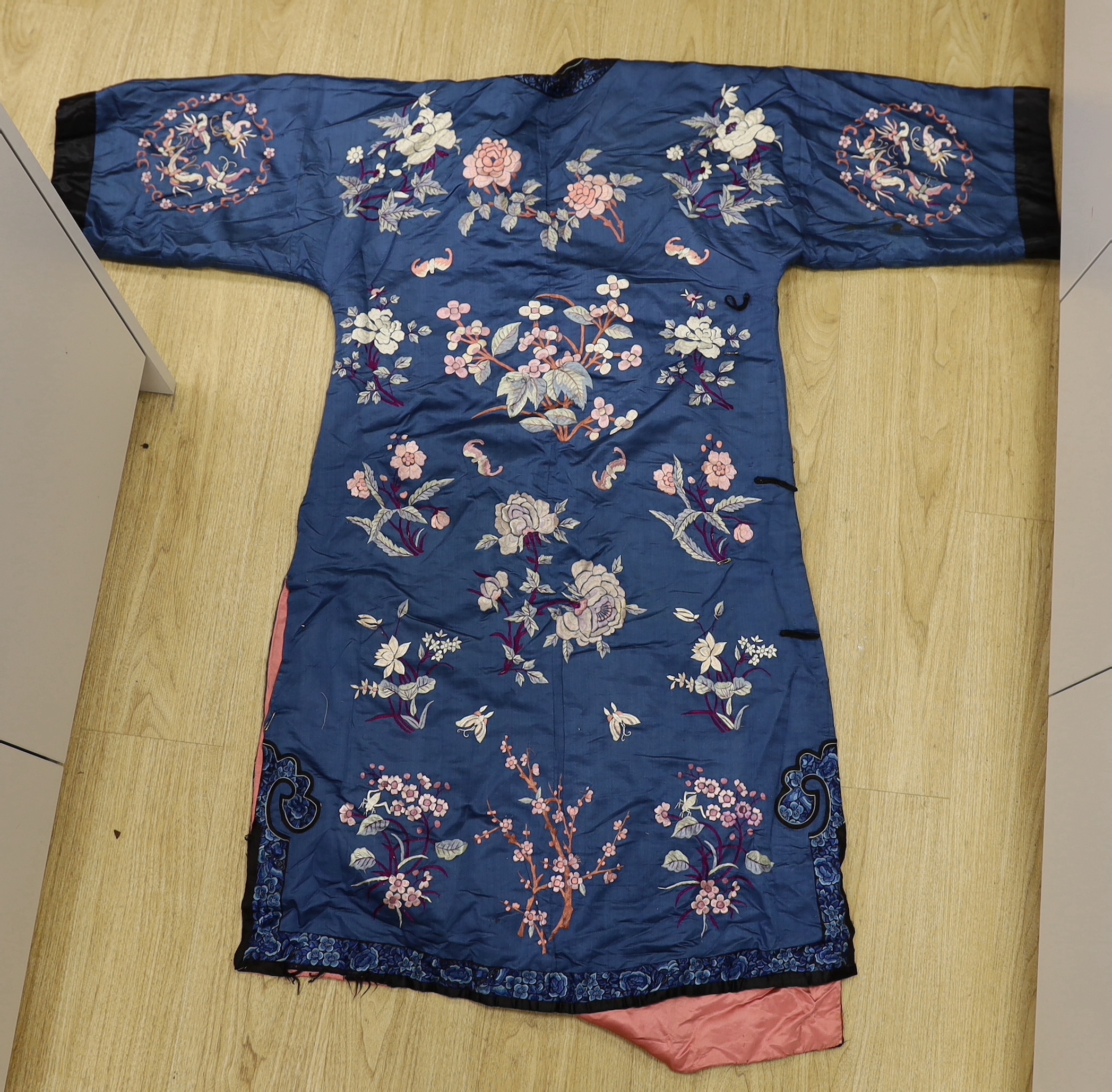 An early 20th century Chinese blue silk embroidered robe, later altered, cut and re-lined, together with various pieces of later Chinese embroidery and an earlier red silk panel with cut velvet circular motifs